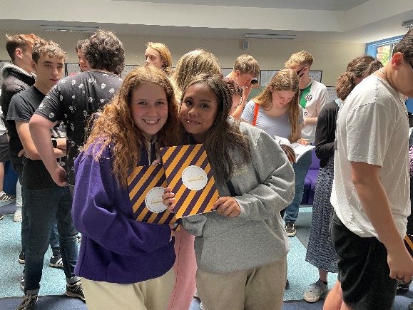 Students holding yearbooks, wearing leavers' hoodies