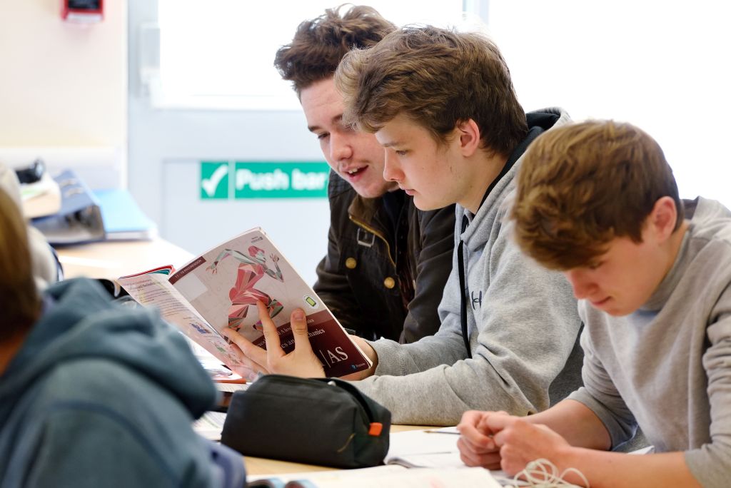 Sixth form students reading an A Level Maths book.