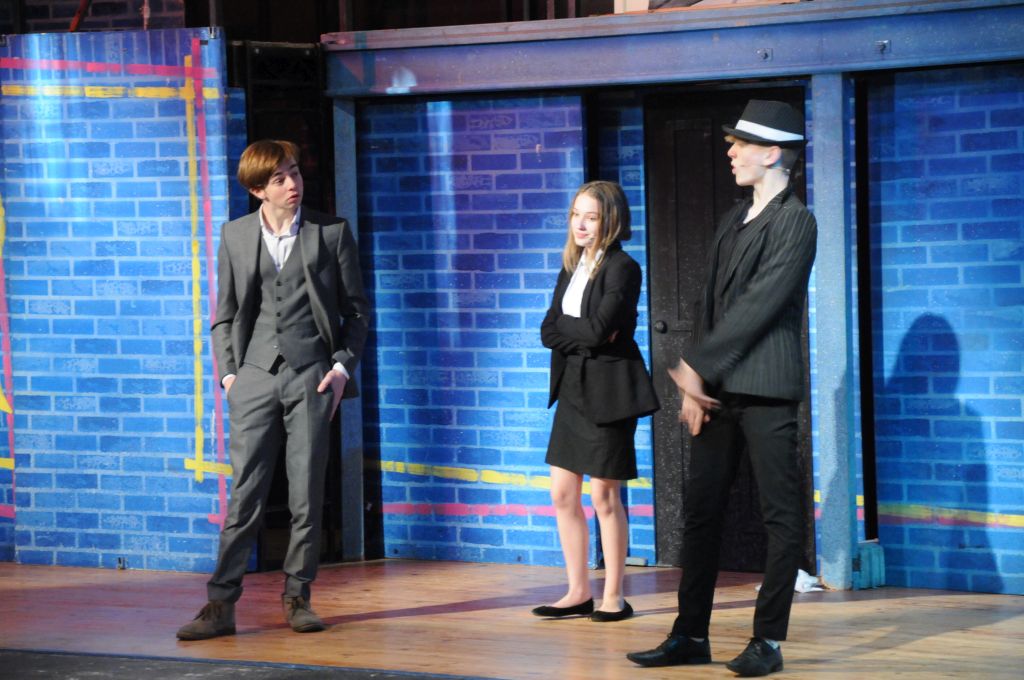 Three characters in smart outfits during Our House production