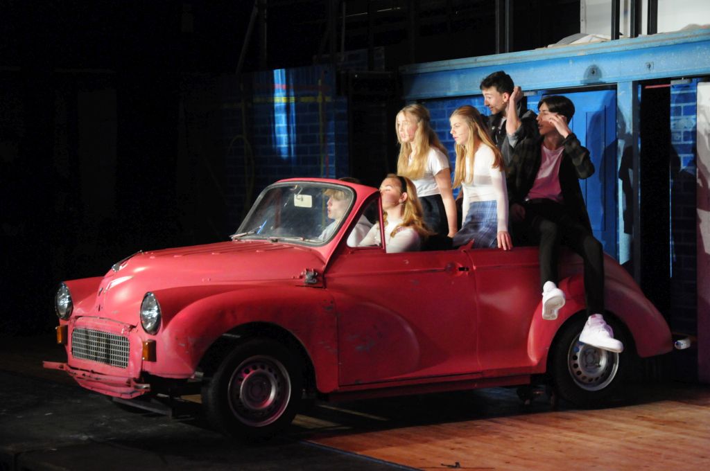 People sat in a red car on stage during Our House