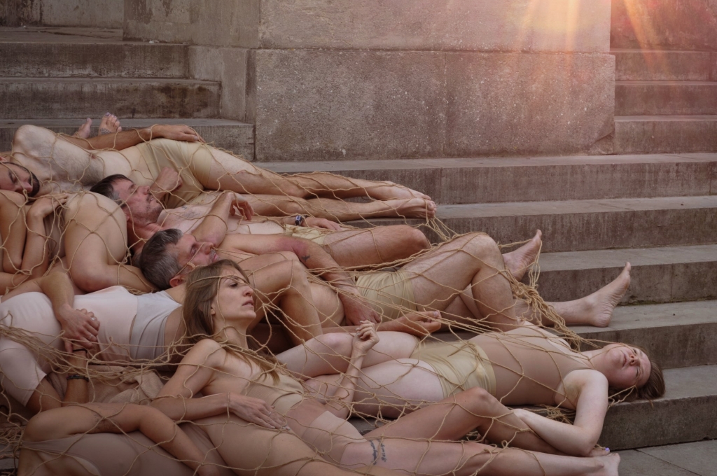 Ezra McHugh (Year 12) - Highly Commended People in buff coloured outfits lying on stone steps under netting